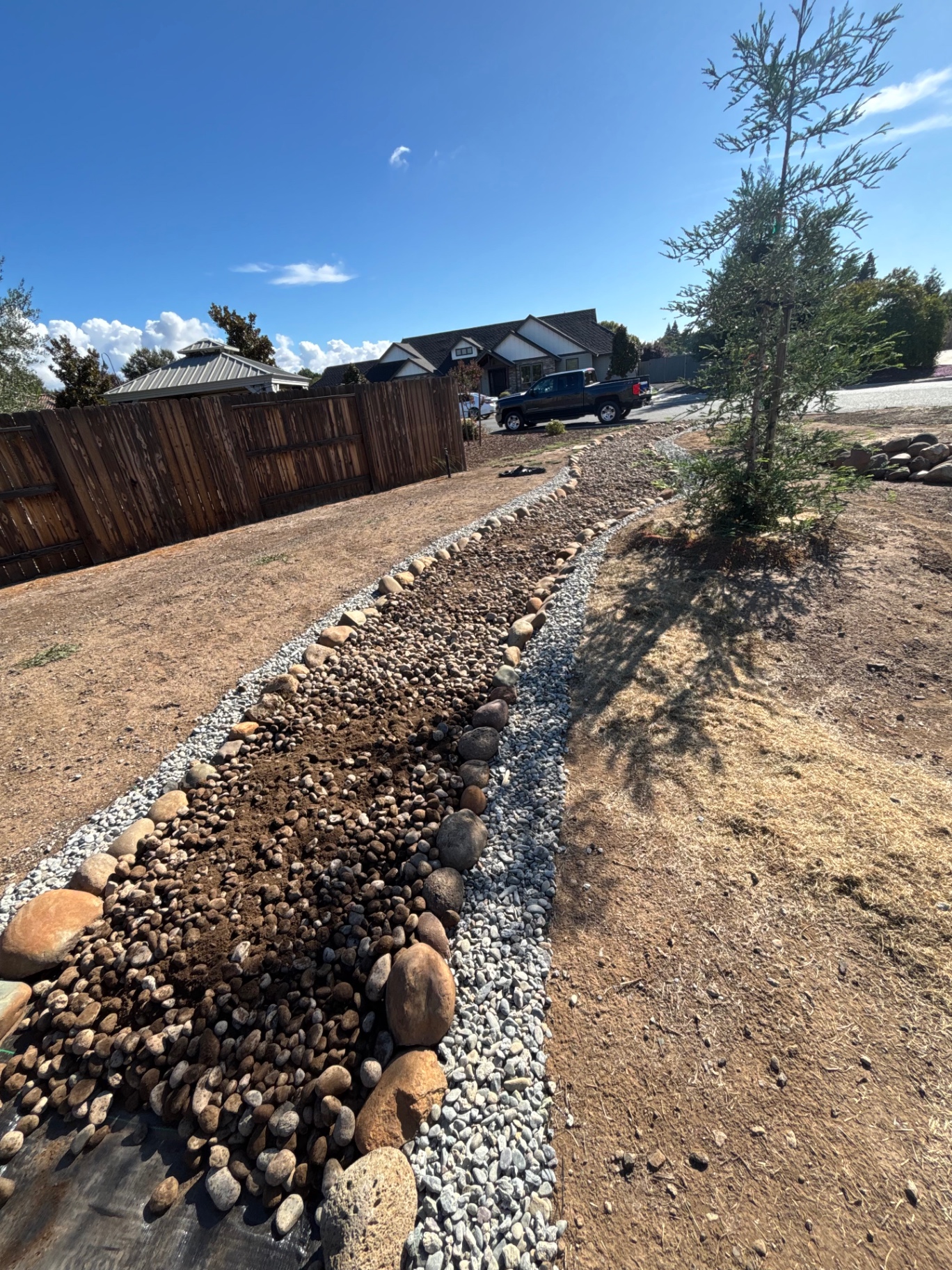 Dry creek bed built from river cobble running the length of a front yard
